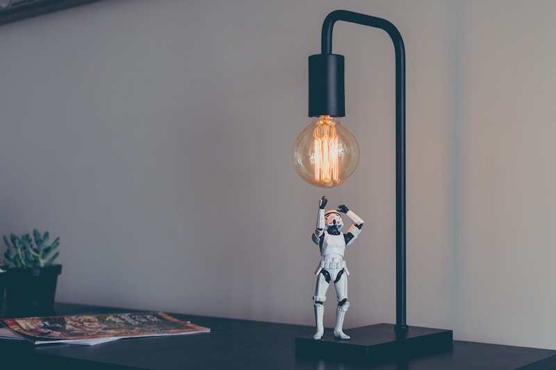 a strormtrooper figurine reaching out to a light bulb